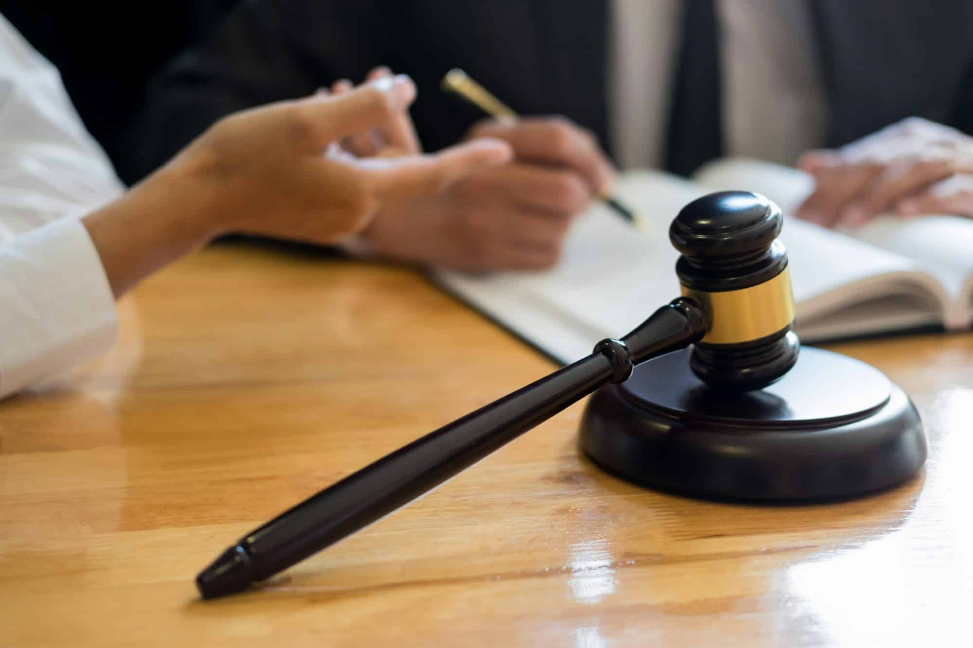 A lawyer and a client review a legal document beside a judge’s gavel