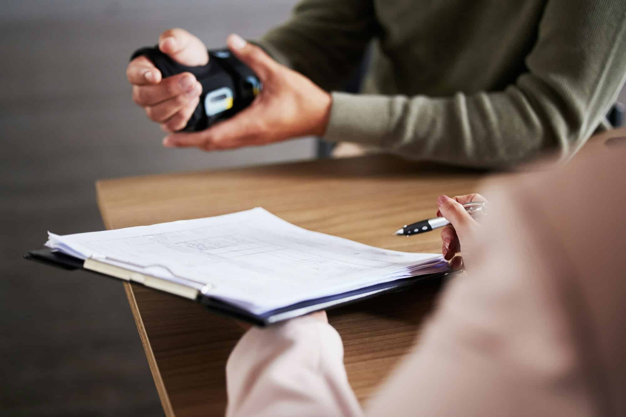 A man in a wrist brace meets with a lawyer who takes notes