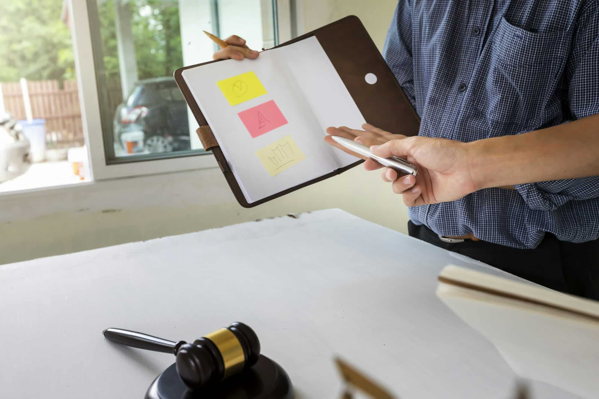 A property owner shows his plans to a lawyer, with a judge’s gavel on the table